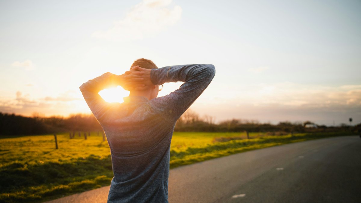 A person at rest on a quiet road at sunset.